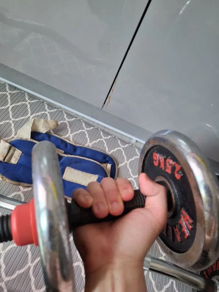 거실 매트 위에 놓인 EZ컬바, 조립식 덤벨, 아령, 악력기, 탁구채 등 다양한 운동기구.