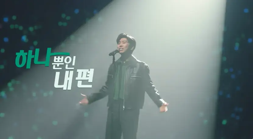 임영웅-
검은 무대 불빛들이 반짝이는 콘서트 장 중앙 검은 가죽쟈켓&#44; 검은 바지를 노래하는 임영웅 좌측에 초록글씨 하나 흰글씨 뿐인 내편