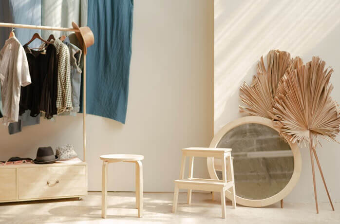 헹거에 걸려있는 옷 네벌과 모자 한 개, 바닥에 세워져있는 동그란 거울