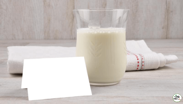 유리컵에 산양유단백질이 담겨있고, 수건과 종이가 바닥에 놓여있다