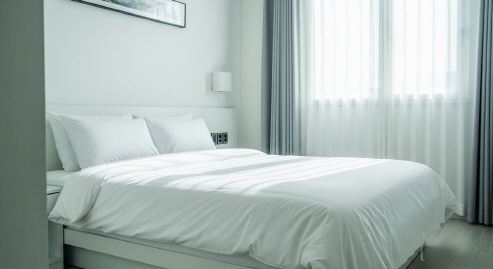 깔끔한 호텔 객실 내부&amp;#44; 하얀 침대와 햇살 가득한 창가