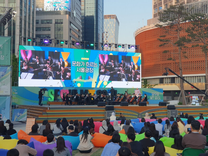 야외무대에서 펼쳐진 클래식 오케스트라 공연, 관객들이 컬러 빈백에 앉아 음악을 감상하는 서울광장 문화행사 모습