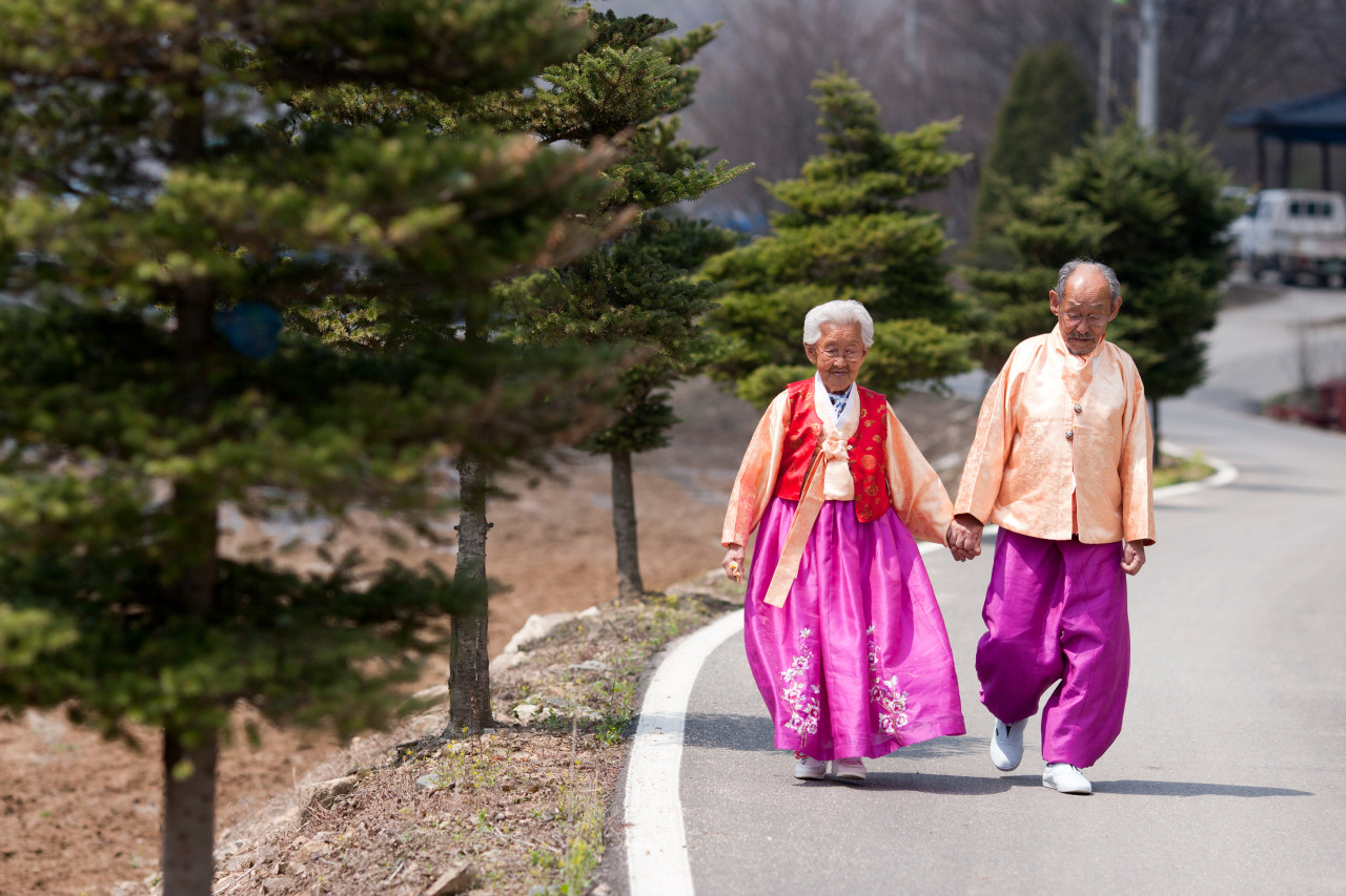 할머니와 할아버지가 손을 잡고 길을 걷는 장면