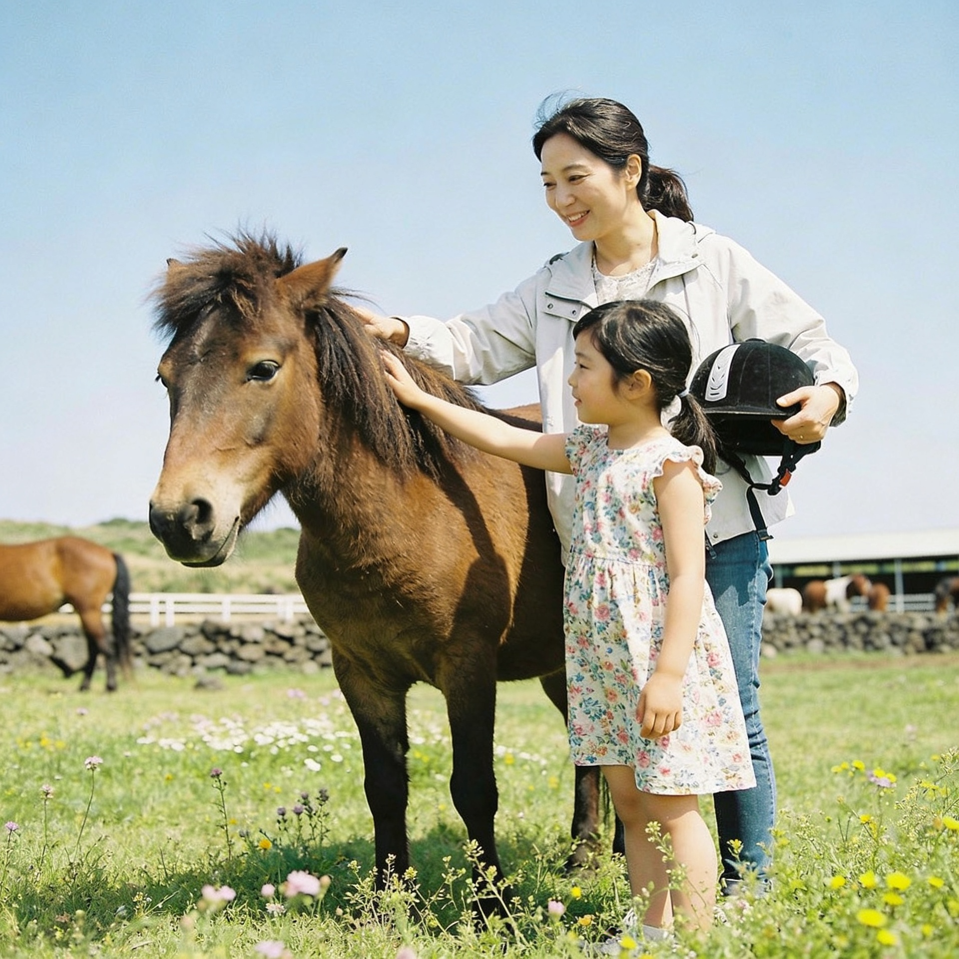 30대 한국 워킹맘과 7살 딸이 제주도의 푸른 초원에서 갈색 제주마 옆에 서서 웃고 있는 모습, 아이가 말 헬멧을 쓰고 있고 목장 배경에 제주 돌담이 보임