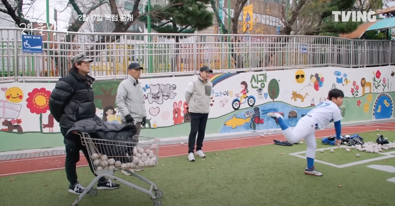 남자 초등학생이 공을 던지고 있고 왼쪽 옆으로 김선우 해설위원, 김성근 감독님, 이택근 선수가 서서 학생을 바라보고 있다.