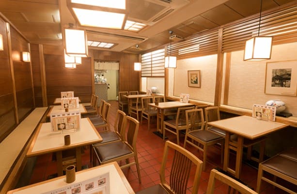 식당의 내부 모습 나무 테이블들과 의자가 놓여져 있다.