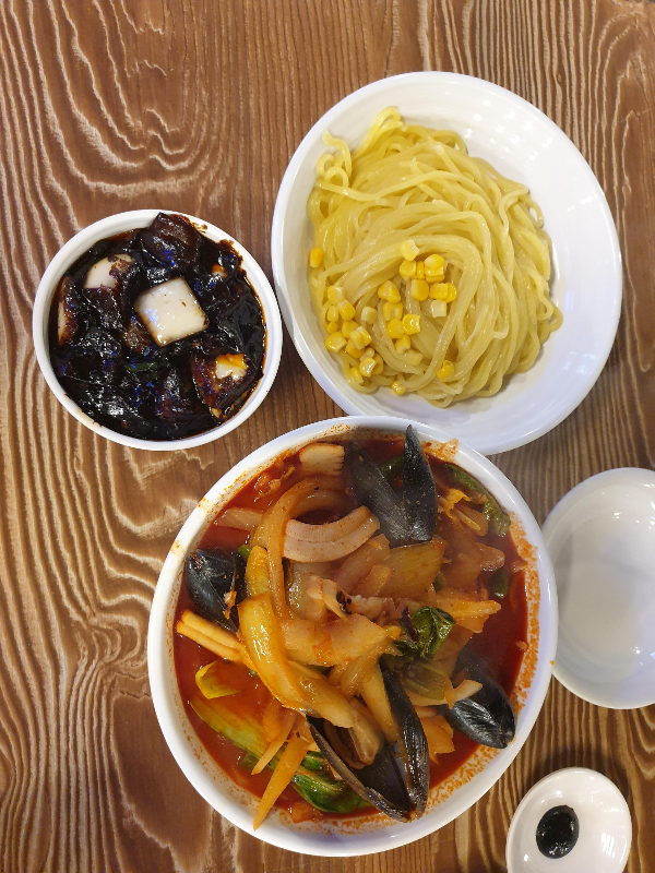 테이블 위에 고추 간짜장의 소스와 면 그리고 고추 짬뽕이 올려져 있다. (위에서 찍은 사진)