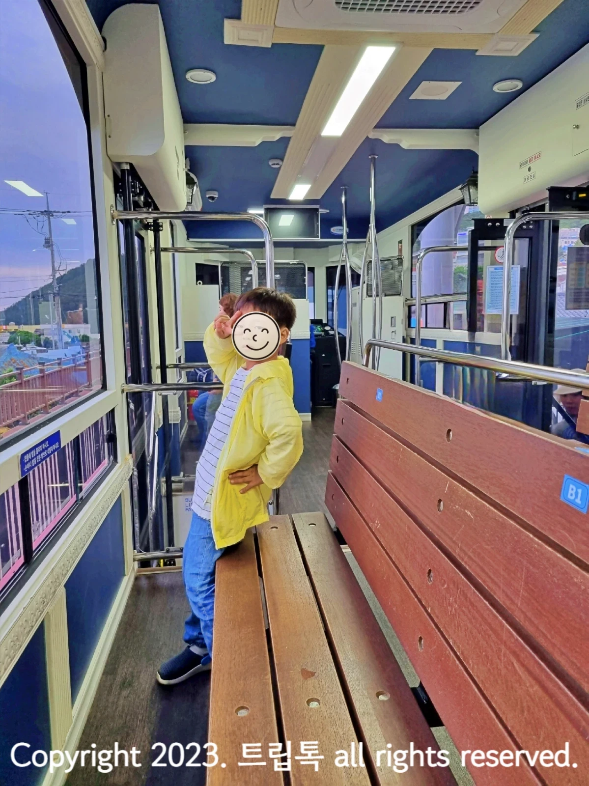 왼쪽에 커다란 유리창문으로 된 해변열차 내부에 나무로 된 의자가 창문쪽으로 설치되어있다