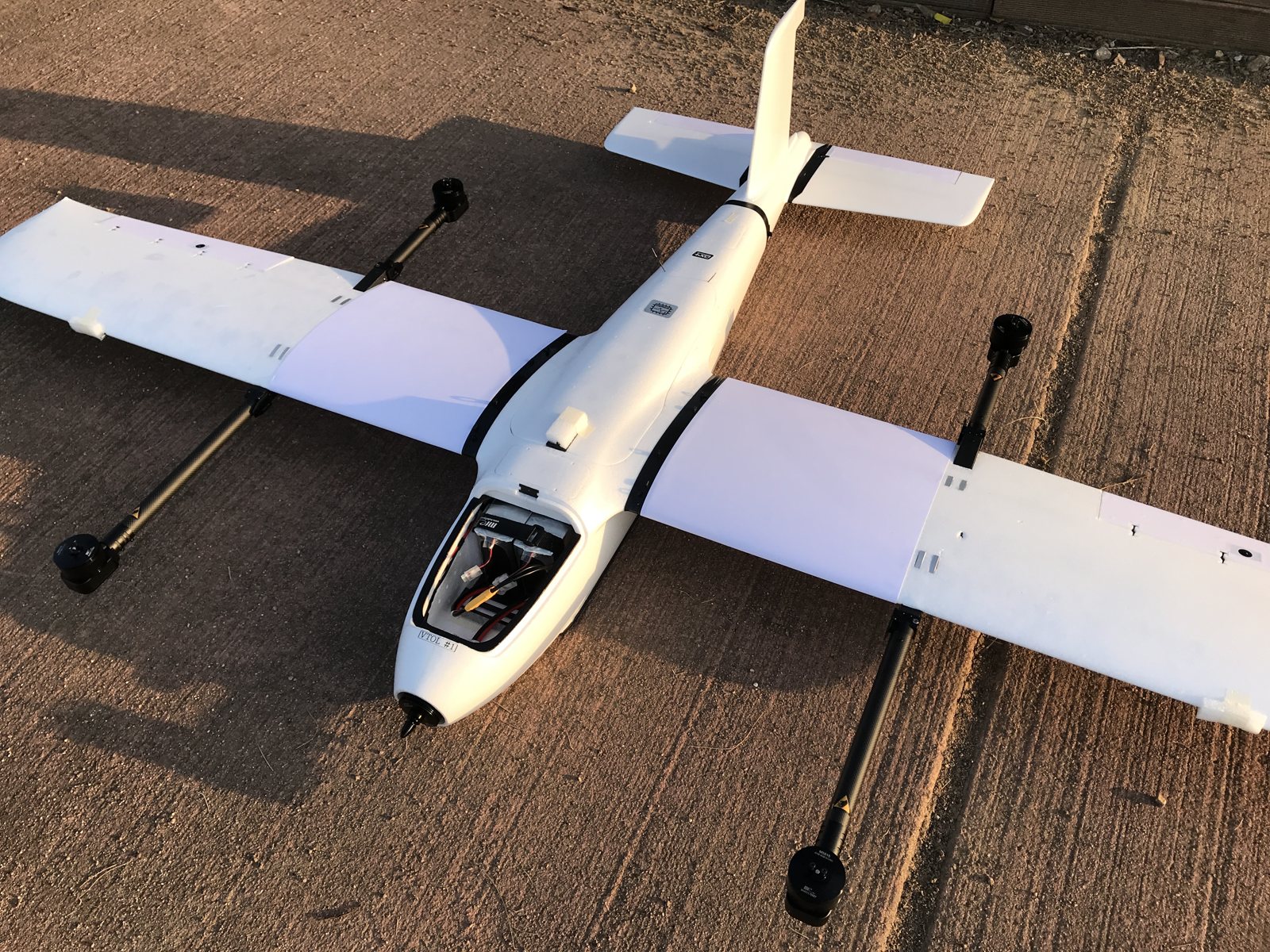 콘크리트 바닥 위에 놓인 흰색 쿼드플레인 VTOL 기체를 앞쪽에서 본 모습