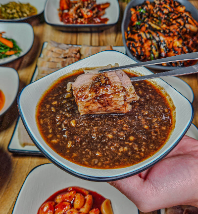 소스에 수육을 찍는 모습