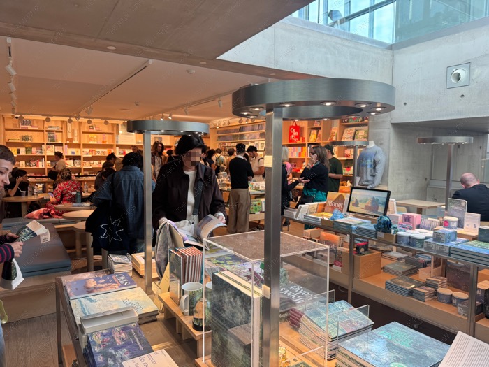 Busy bookstore and souvenir shop area at Musée de l'Orangerie with visitors browsing books and items.