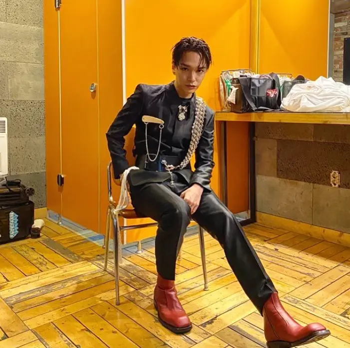 환승연애3- 노란색 가구와 노란색 화장대가 있는 실내 검은색 위하래 가죽옷에 빨간색 가죽부츠를 신고 철제의자에 앉아있는 사이먼도미닉