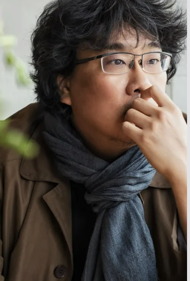 봉준호 감독이 왼손을 입에 가져다 대고 먼 곳을 응시한는 사진