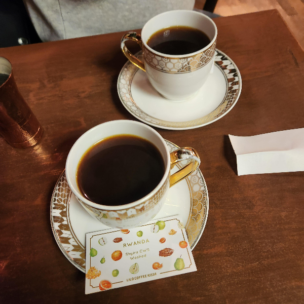 우드 테이블 위에 고풍스런 커피잔 두 개가 올려져 있다.