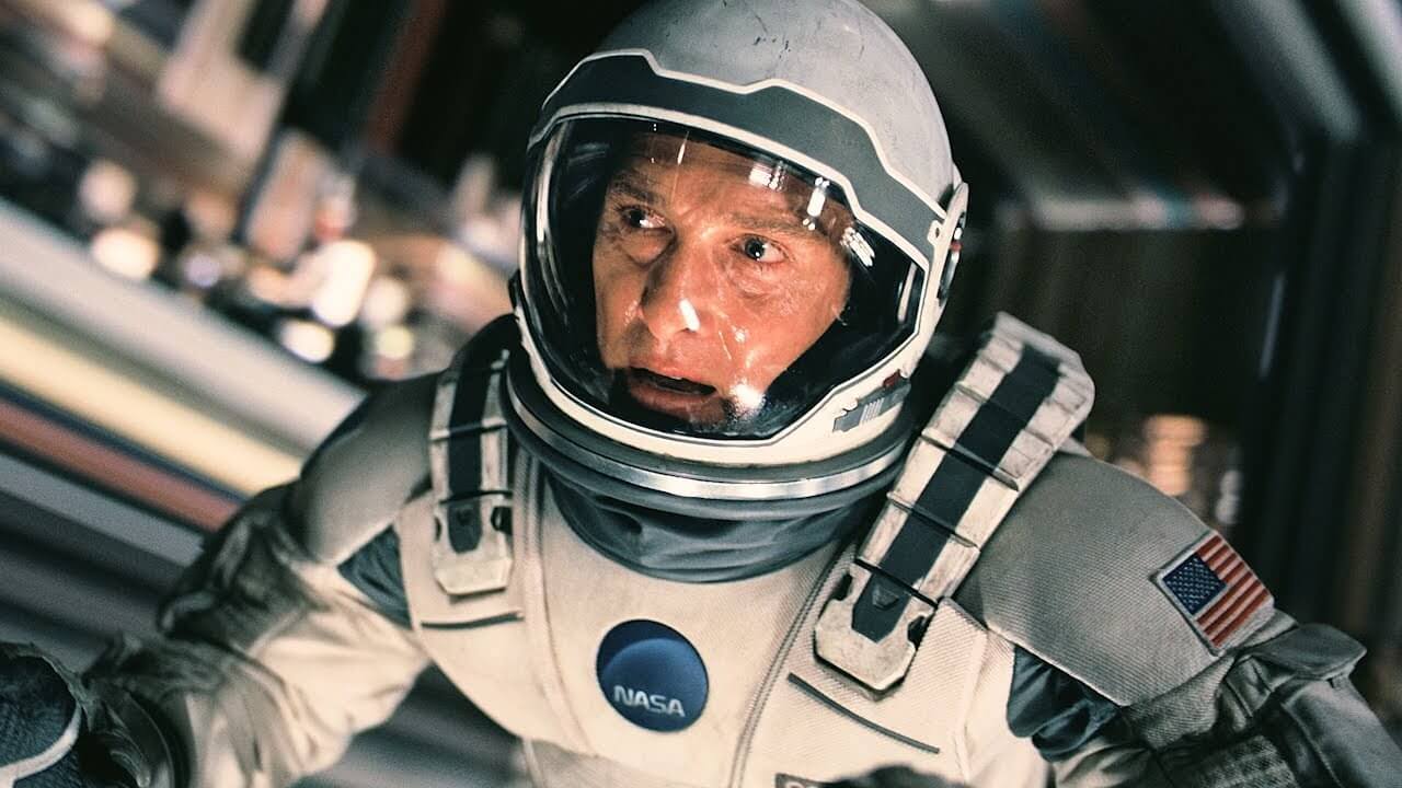 인터스텔라에서 우주복을 입은 쿠퍼가 긴장된 표정으로 우주선 내부를 응시하는 장면