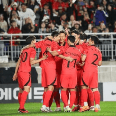 빨간 축구 국가대표 유니폼을 입고 서로 껴안으며 기뻐하는 선수들