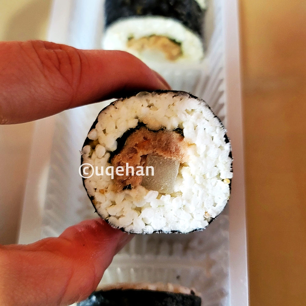 노브랜드 든든한 한끼 참치마요 김밥을 손가락을 집어 들고 있다.