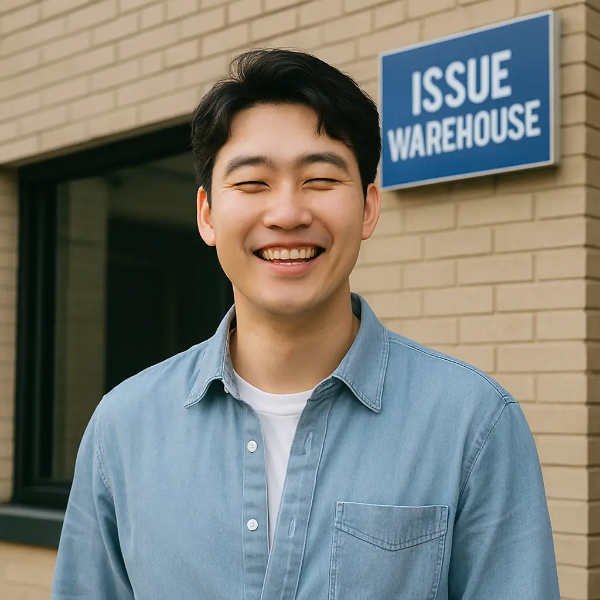‘ISSUE WAREHOUSE’ 건물 앞에서 환하게 웃고 있는 청년의 텍스트 없는 인물 이미지
