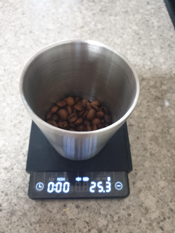 저울 위에 스텐레스 컵에 원두 25g이 담겨 있다.