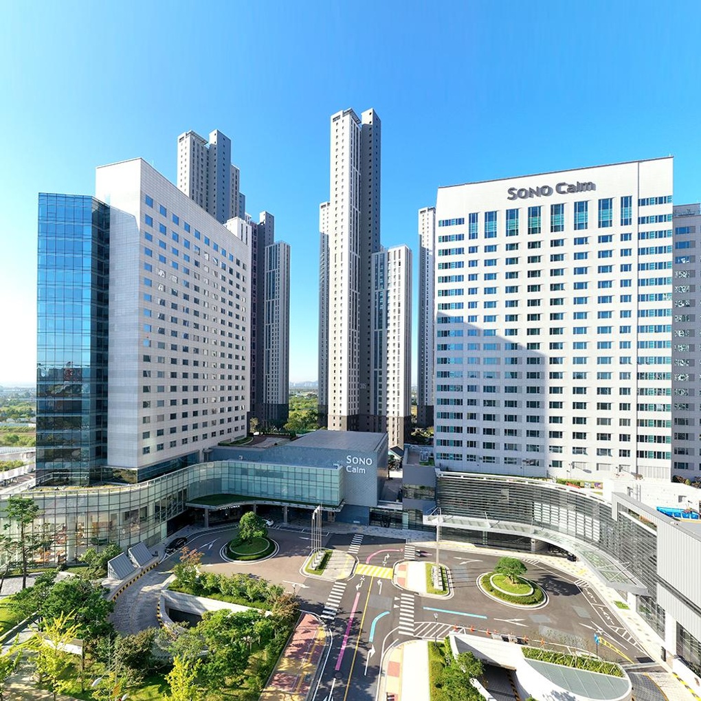경기도 고양시에 위치한 소노캄 고양 호텔 전경. 현대적인 고층 건물이 푸른 하늘 아래 우뚝 솟아 있으며, 주변에는 정돈된 녹지와 도로가 깔끔하게 조성되어 있다.