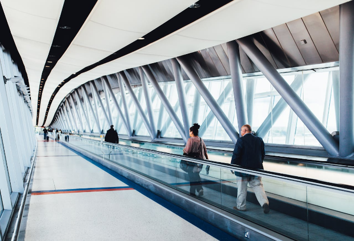 Travelers on an escalator in an airport, symbolizing life&rsquo;s thresholds and moments of reflection.
