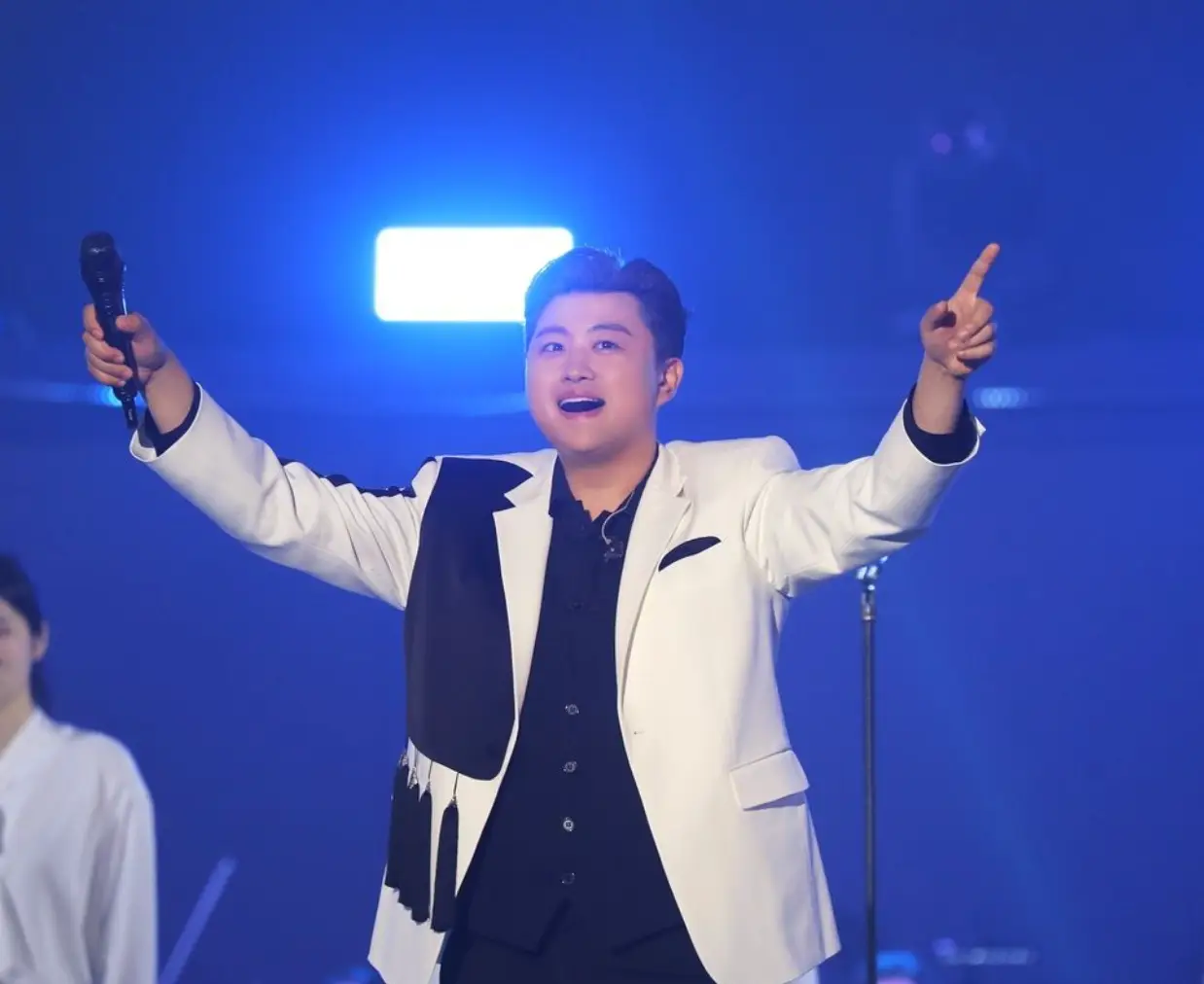 파란무대배경 흰옷을 입은 김호중이 두팔벌린채 노래하는 모습