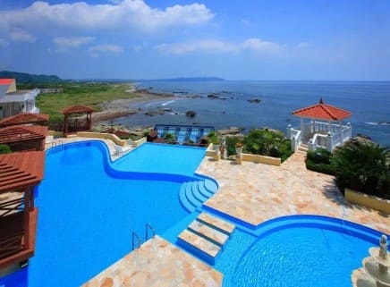 푸른 수영장이 보이고 그 뒤로 바다가 보인다.