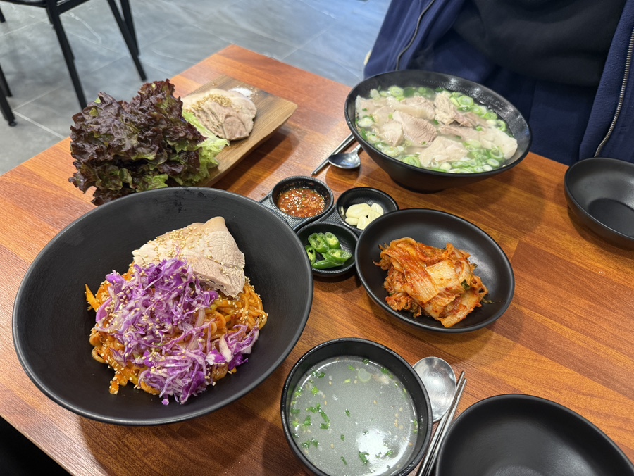 고기국수, 비빔국수, 돔베고기가 한 테이블에 풍성하게 차려져 있는 사진. 뜨끈한 국수와 제주식 수육이 어우러진 푸짐한 한상이 담겨 있다.