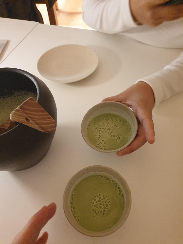 흰색 테이블 위 말차 항아리와 말차를 담은 술잔 두 개