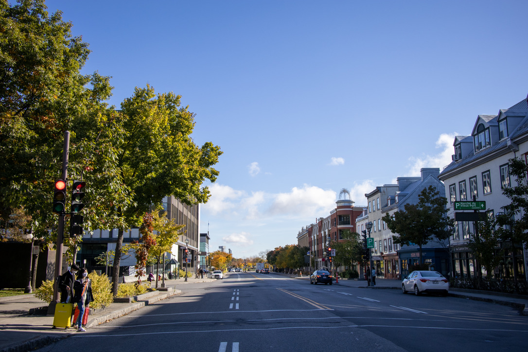 4차선 도로를 기준으로 왼쪽은 푸른 나무들이 보이고, 오른쪽은 주택들이 세개 보인다.