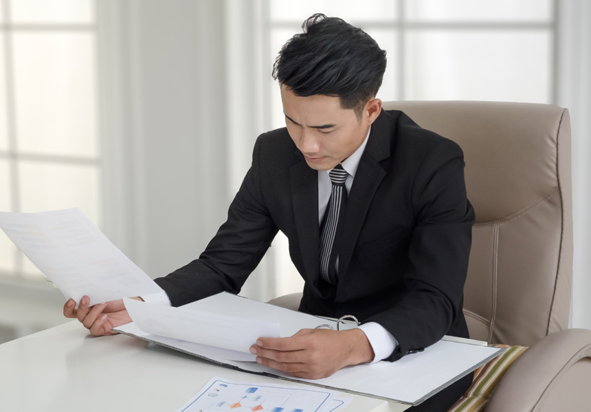 정장 차림의 투자자가 서류를 검토하며 투자 전략을 세우는 모습