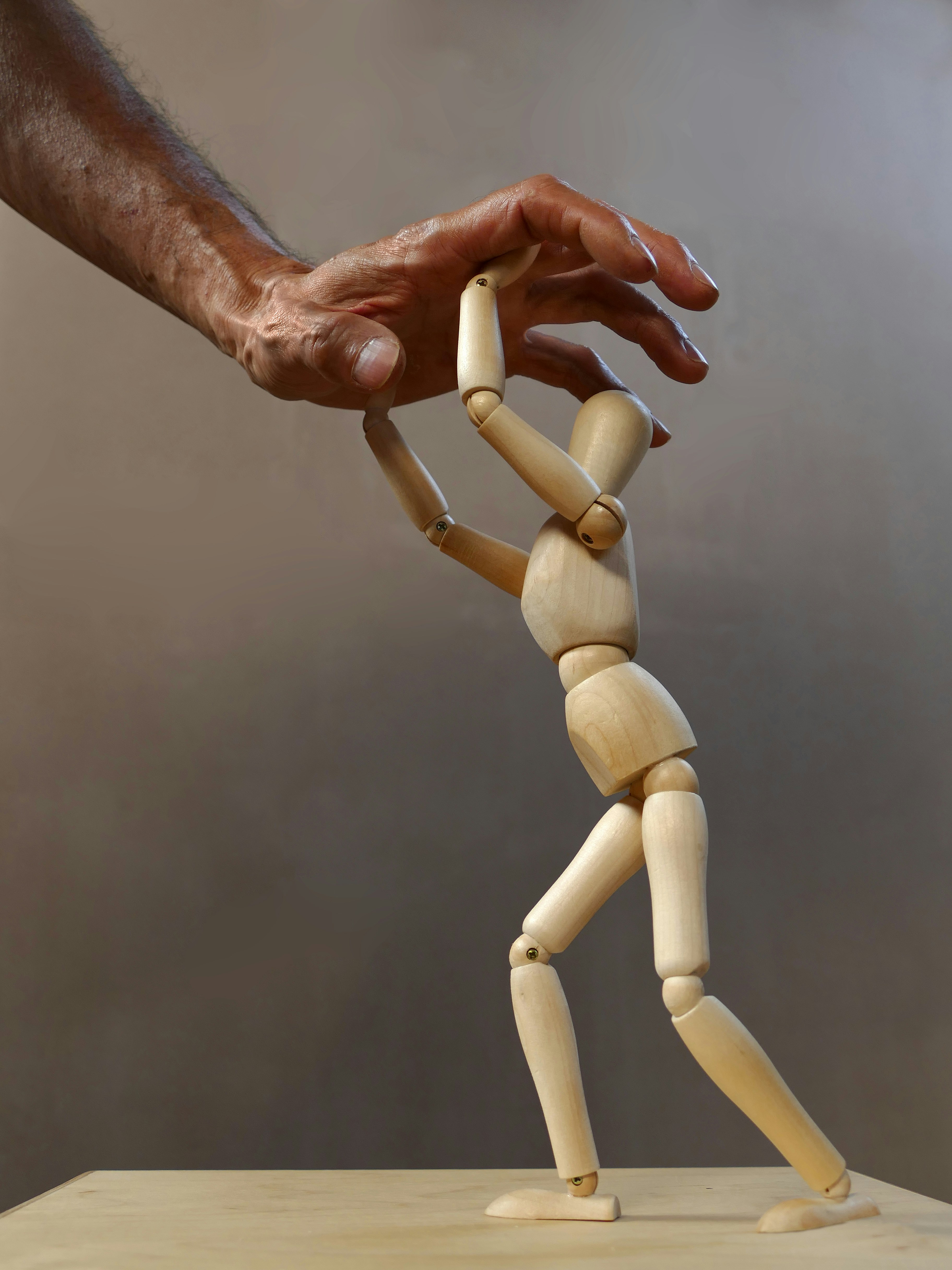 작은 목각 인형이 사람의 손을 받치고 있는 이미지