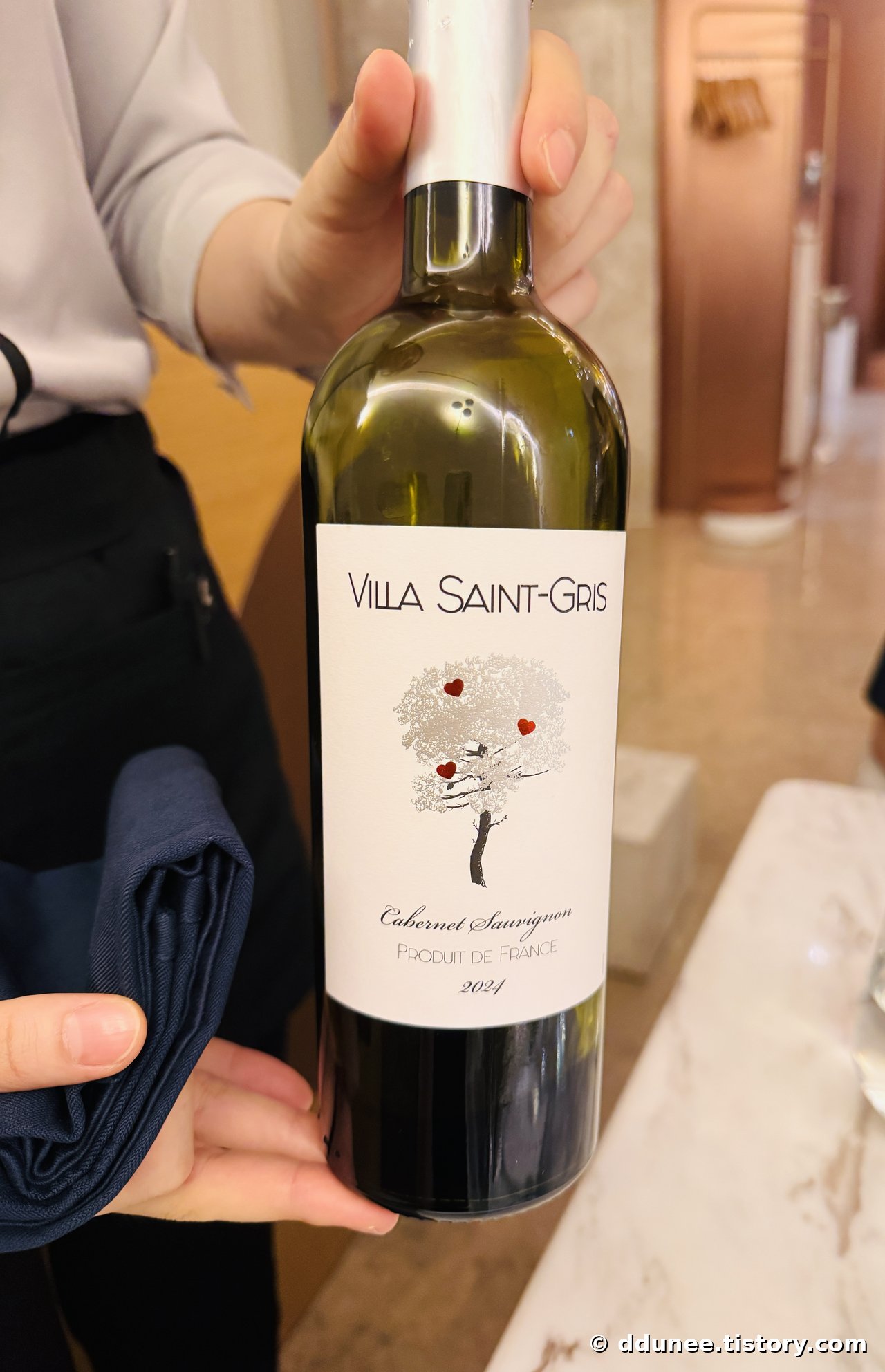 서버가 테이블에서 보여주는 프랑스산 Villa Saint-Gris 카베르네 소비뇽 와인 병