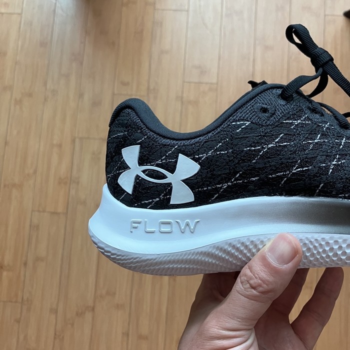 손에 들고 있는 언더아머 플로우 벨로시티 윈드 2 러닝화 후족부와 로고 클로즈업