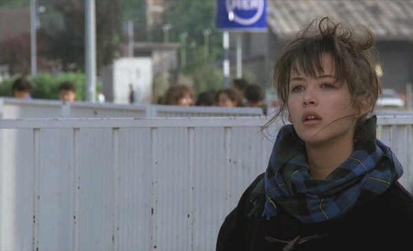 'You Call It Love'에서 멀리 응시하는 체크무늬 스카프의 여주인공