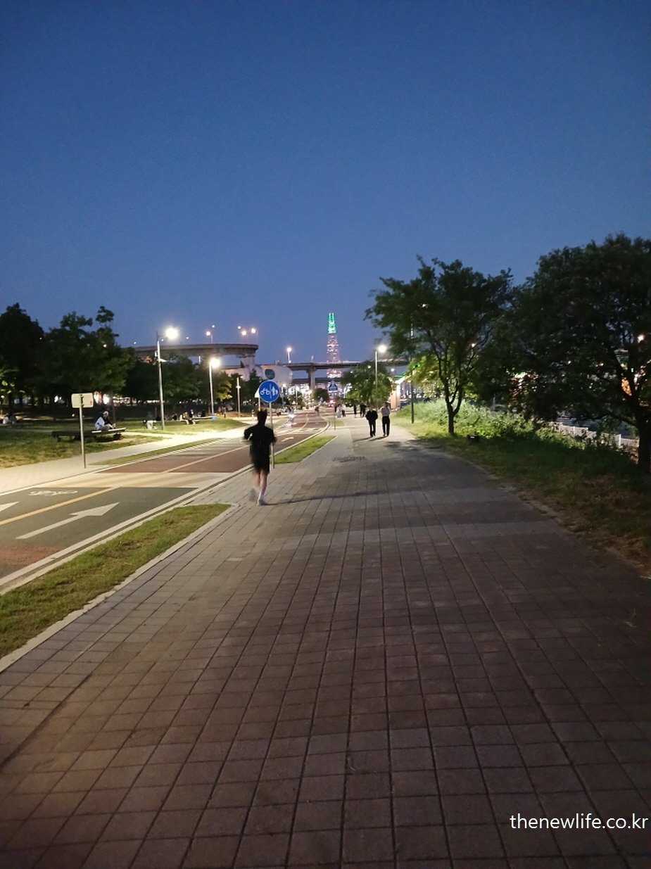 Woman jogging under night lights &ndash; representing emotional stability and calm in evening jogs.-야경 속에서 조깅하는 여성 &ndash; 조용한 저녁 시간의 정서신적 안정감을 보여줍니다.