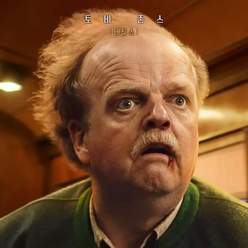 초록색 티를 입고 대머리에 콧수염이 있는 바질쇼의 놀란 얼굴