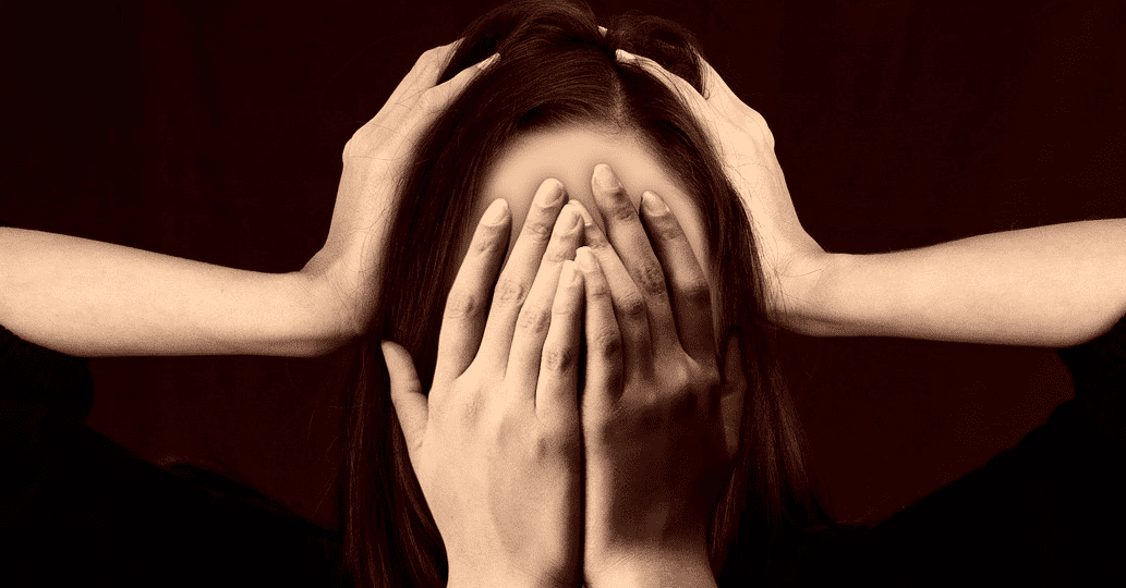 머리에 양손을 올리고 두통을 호소하는 여성