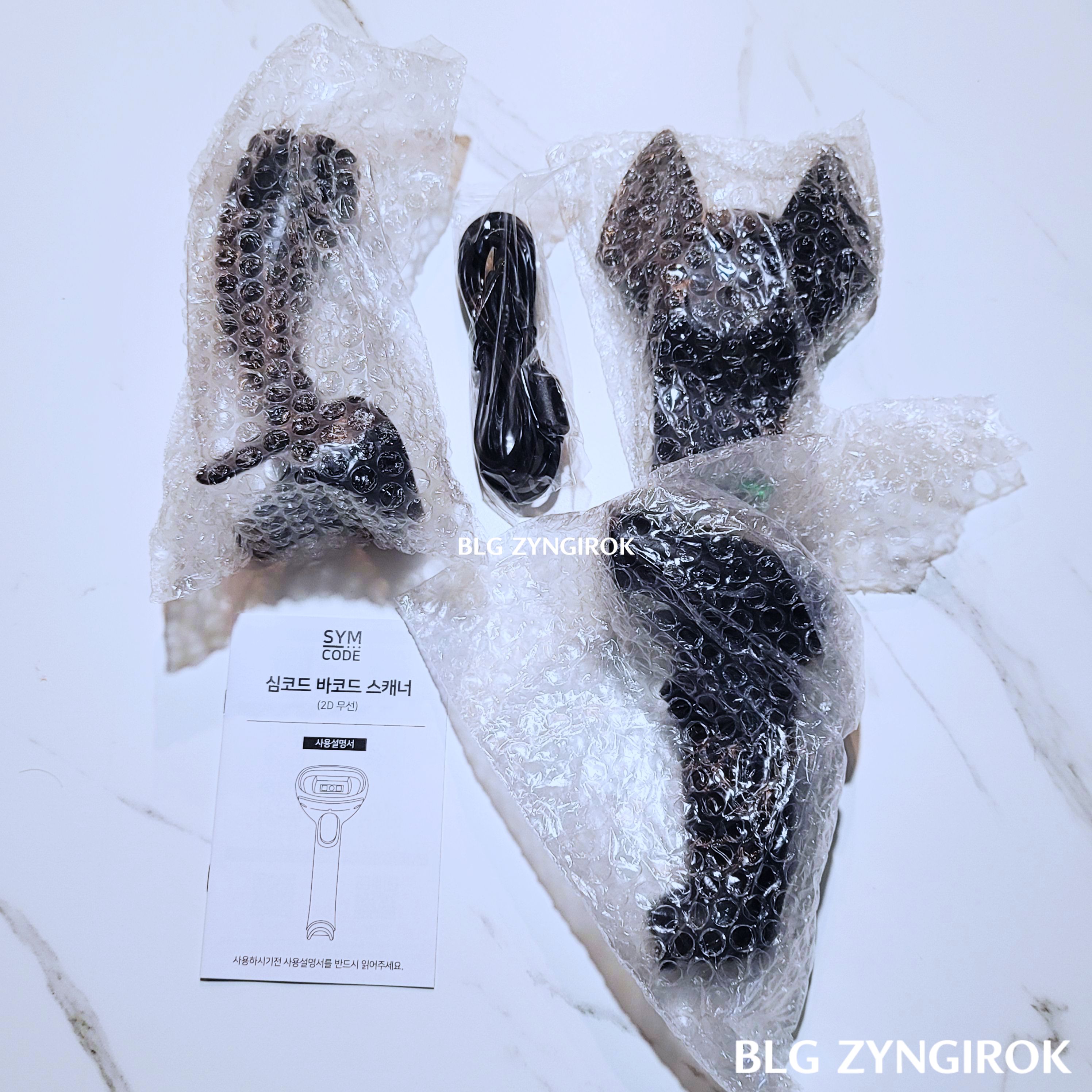 심코드-바코드-스캐너-구성품들이-뽁뽁이-봉투에-쌓여-놓여있다.-거치대-usb-케이블-거치대의-지지대-설명서-그리고-본체가-순서대로-놓여있다.