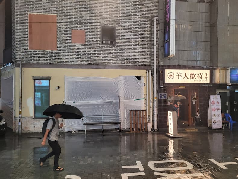 비 오는 날 우산을 쓰고 거리는 걷는 남자