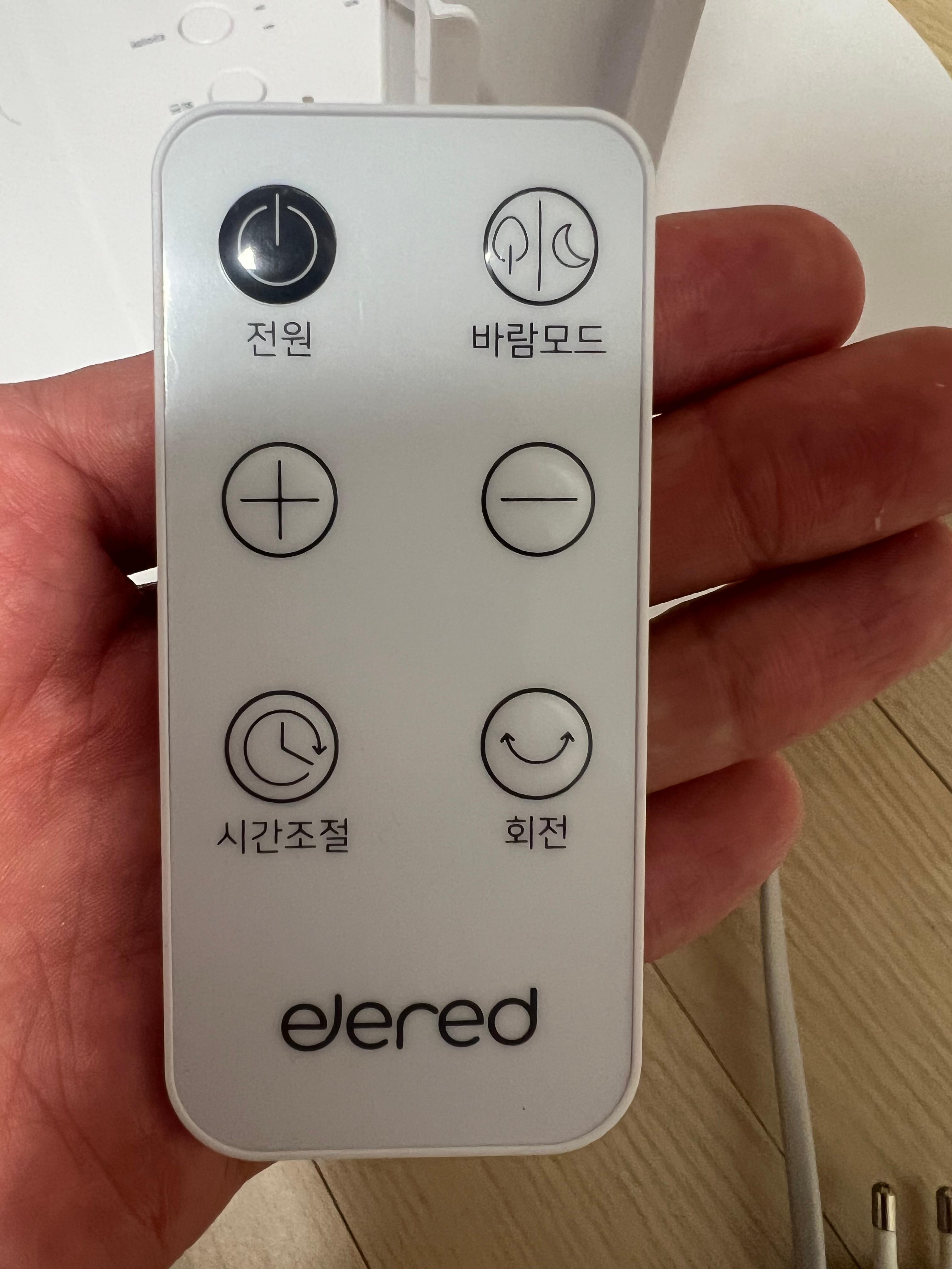 일레드 EDF-2414W 리모컨 버튼 구성 클로즈업 &mdash; 손바닥 위에 올린 6버튼 흰색 리모컨, 바람모드&middot;풍속&middot;회전&middot;전원 버튼이 선명