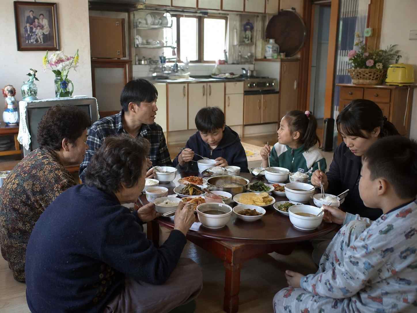 명절 다음 날 아침 친척집 식탁에 둘러앉아 함께 식사하는 가족과 아이들