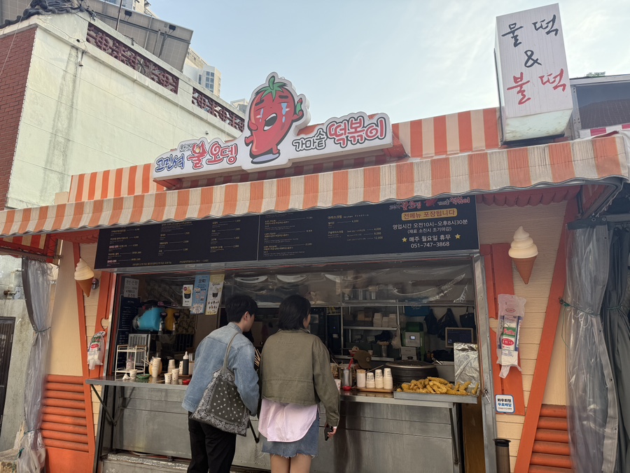 부산 해운대 해리단길에 있는 고민석불오뎅가마솥떡볶이 외관 모습으로 포장마차 스타일의 분위기와 웨이팅 줄이 보이는 분식 맛집