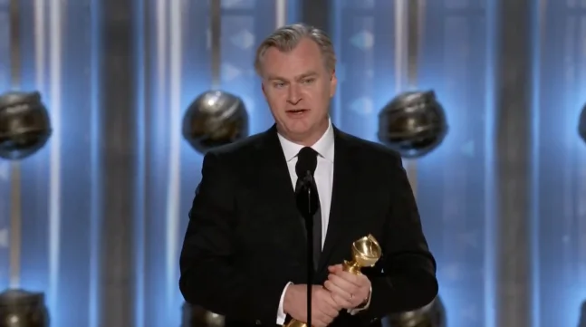 크리스토퍼 놀란 감독이 시상식 무대에서 트로피를 들고 수상 소감을 전하는 장면