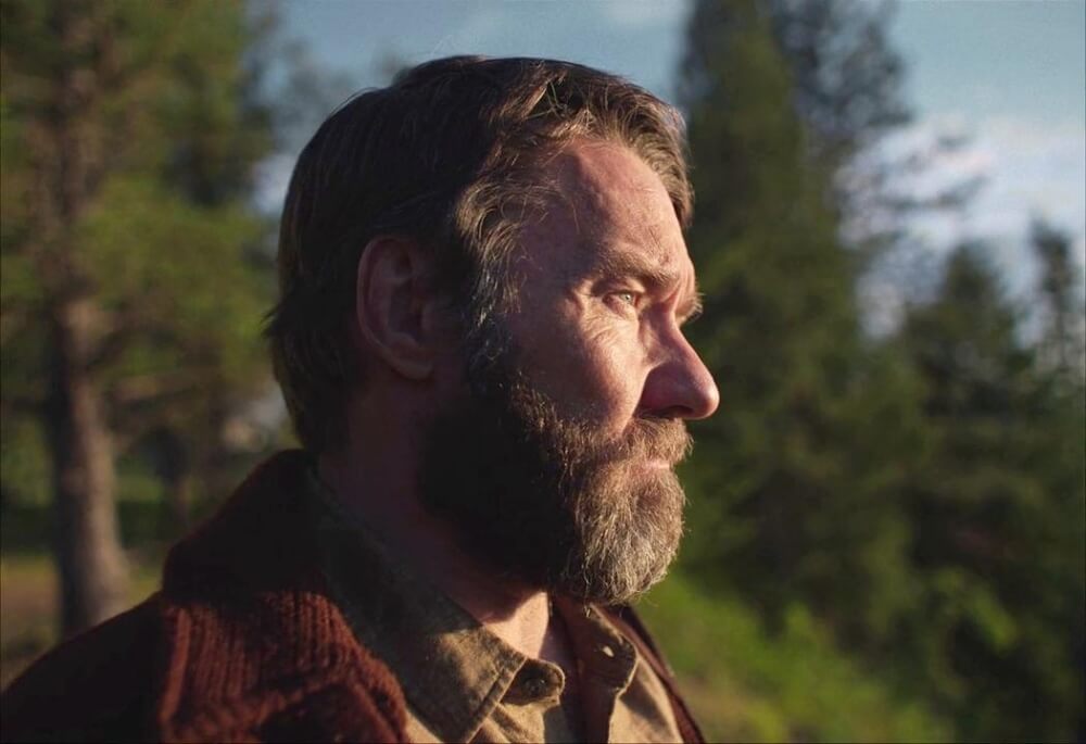 영화 기차의 꿈 스틸컷 – 벌목 캠프에서 고독한 표정으로 서 있는 로버트