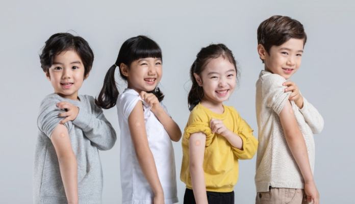 아이들이 주사를 맞은 팔을 보여주고 있다.