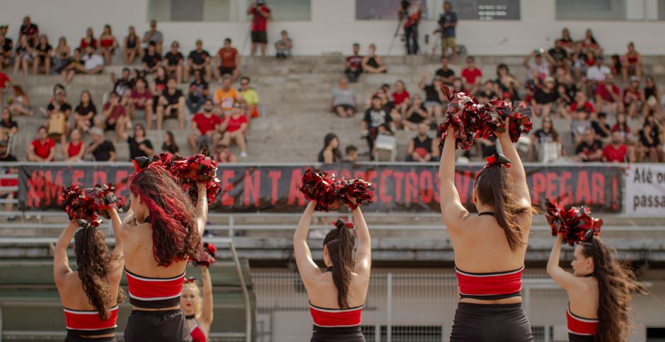 Cheerleaders with pom-poms performing at a sports event in an outdoor stadium.