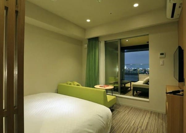 시내를 바라볼 수 있는 테라스를 가진 호텔의 실내 객실 사진 침대와 소파가 테라스를 향해 놓여져 있다.