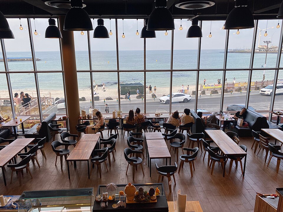 제주 월정리 해변 앞 카페 2층에서 내려다본 넓은 실내 좌석과 통유리창 너머 바다