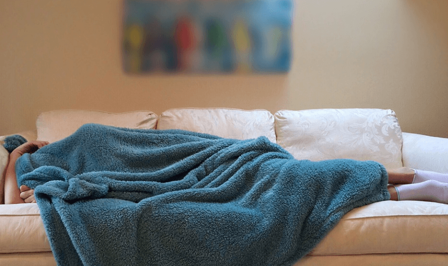소파에 머리까지 이불을 덮고 자고 있는 사람